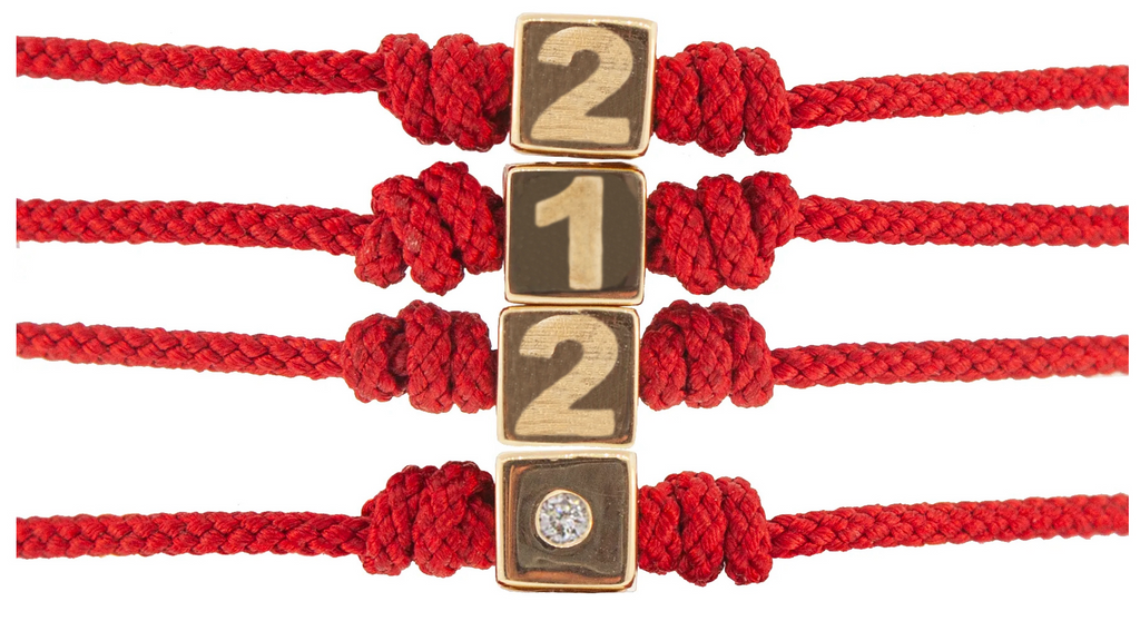 LUIS MORAIS 14k yellow gold cube with engraved 212 area code and white diamond on a red cord bracelet.