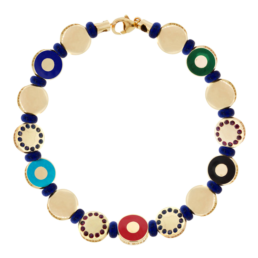 LUIS MORAIS 14k yellow gold bracelet features enameled evil eyes, plain disks, and  reversible disks with blue sapphires on one side and rubies on the other, separated by lapis beads. 14k yellow gold lobster clasp closure.