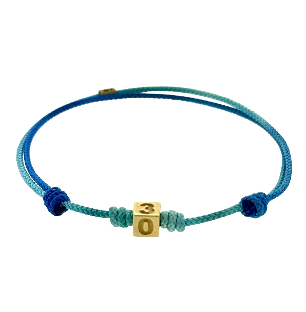 LUIS MORAIS 14K yellow gold cube with engraved 305 Miami area code and a ruby stone on a blue ombre adjustable cord bracelet.   