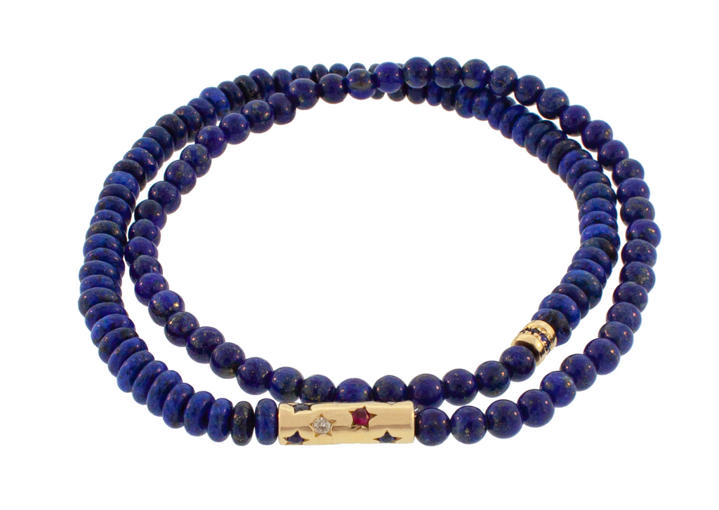 LUIS MORAIS 14K gold tube featuring ruby, white diamond, and blue sapphire stars and a short roll with blue sapphires on a double-wrap lapis beaded bracelet.