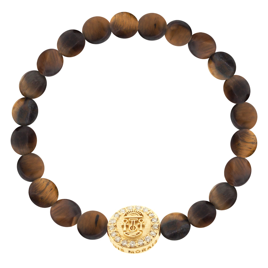 LUIS MORAIS 14K yellow gold large disk with a good luck symbol surrounded by white diamonds on medium tiger's eye disks on a beaded bracelet. The symbol and diamonds are on both sides of the gold. 