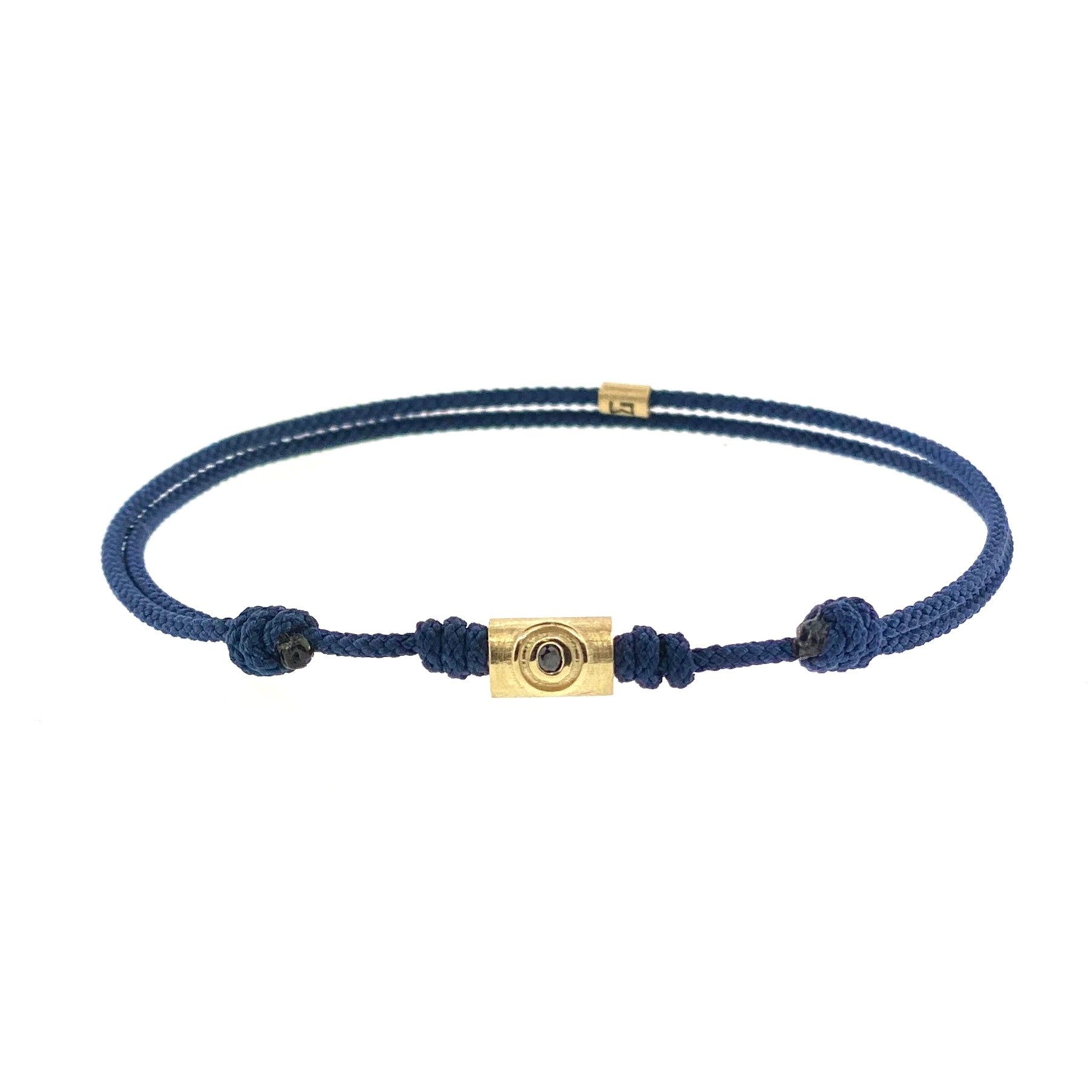 A blue cord bracelet with a yellow gold matte tube featuring an evil eye relief and a black diamond, alongside gold spherical accents.