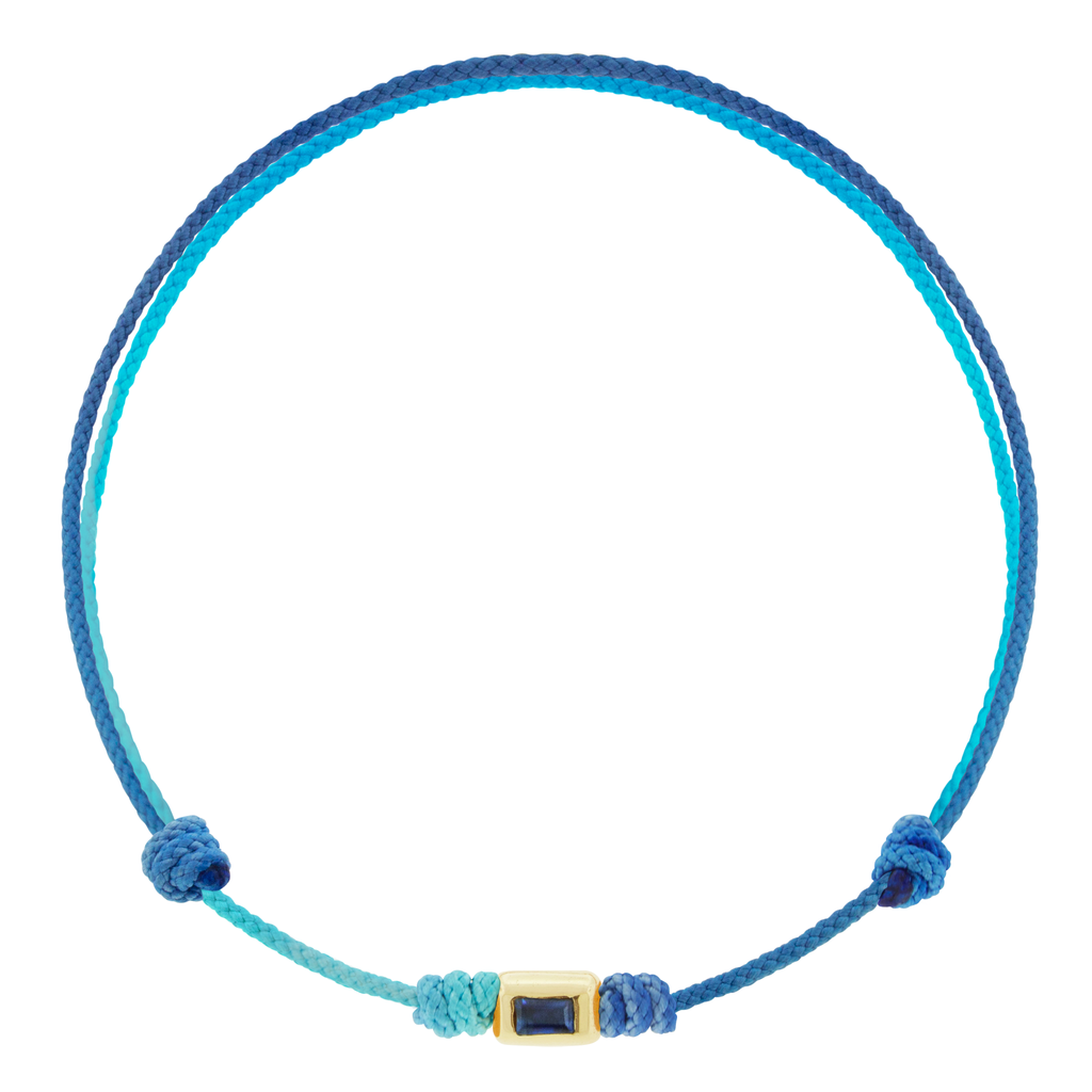 LUIS MORAIS 14k yellow gold small ingot with a baguette blue Sapphire on a cord bracelet.