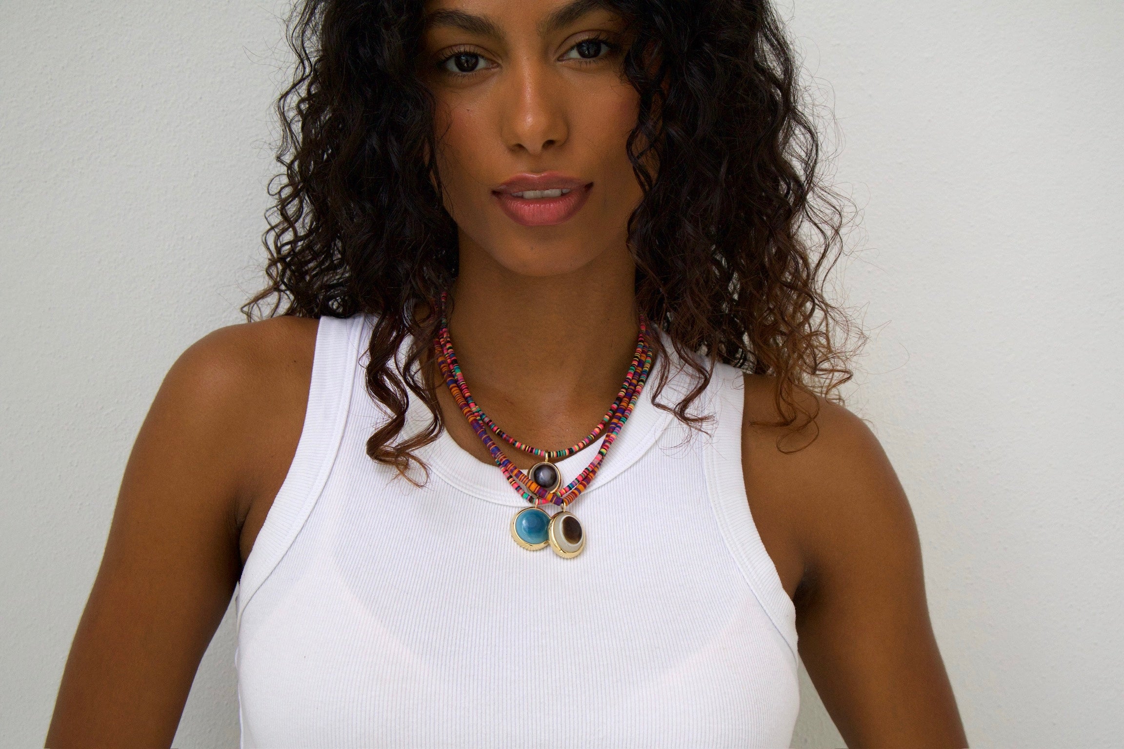Woman wearing a colorful necklace against a plain background