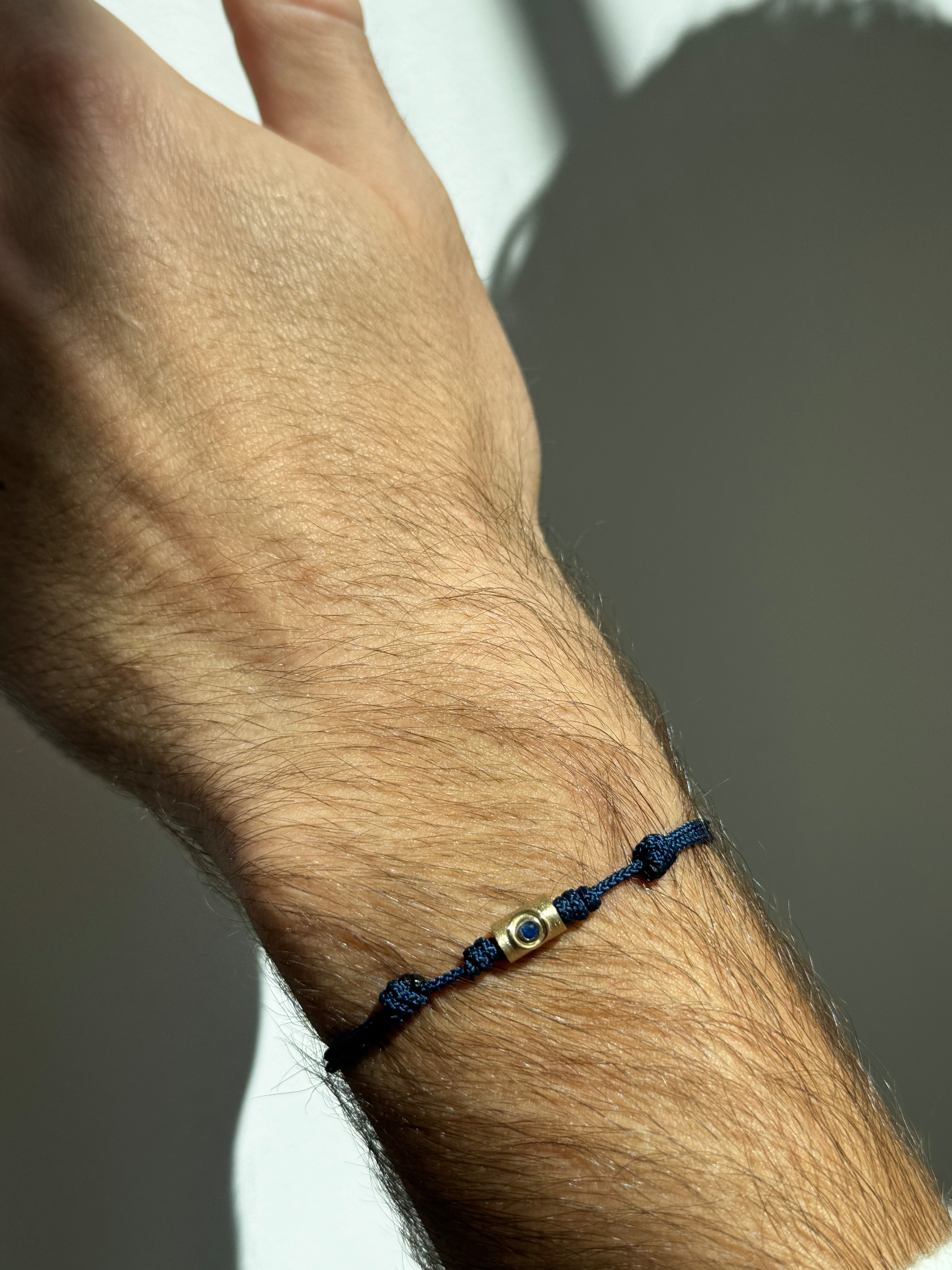 Gold Eye Tube with Blue Sapphire on Navy Cord Bracelet