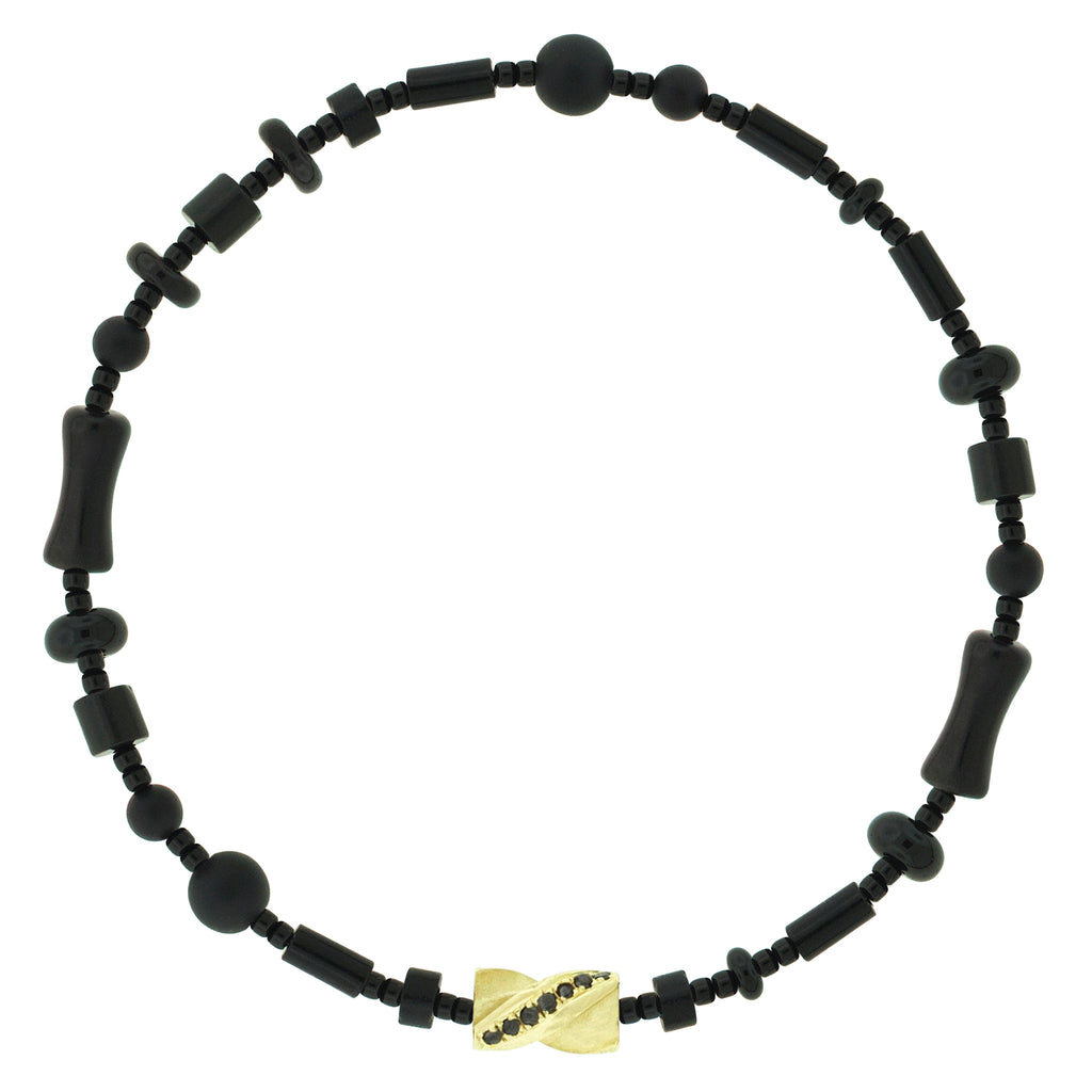 LUIS MORAIS 14k yellow gold drill bit with diamonds on a gemstone and glass beaded bracelet. The drill bit design is symbolic of digging deeper into oneself and life’s challenges. It represents resilience and the pursuit of discovery, encouraging the wearer to push through obstacles and uncover hidden truths.