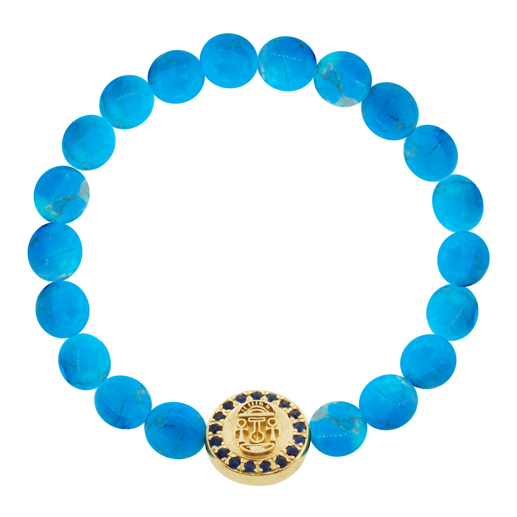 LUIS MORAIS 14K yellow gold large disk with a good luck symbol surrounded by blue sapphires on medium turquoise disks on a beaded bracelet. The symbol and diamonds are on both sides of the gold. 