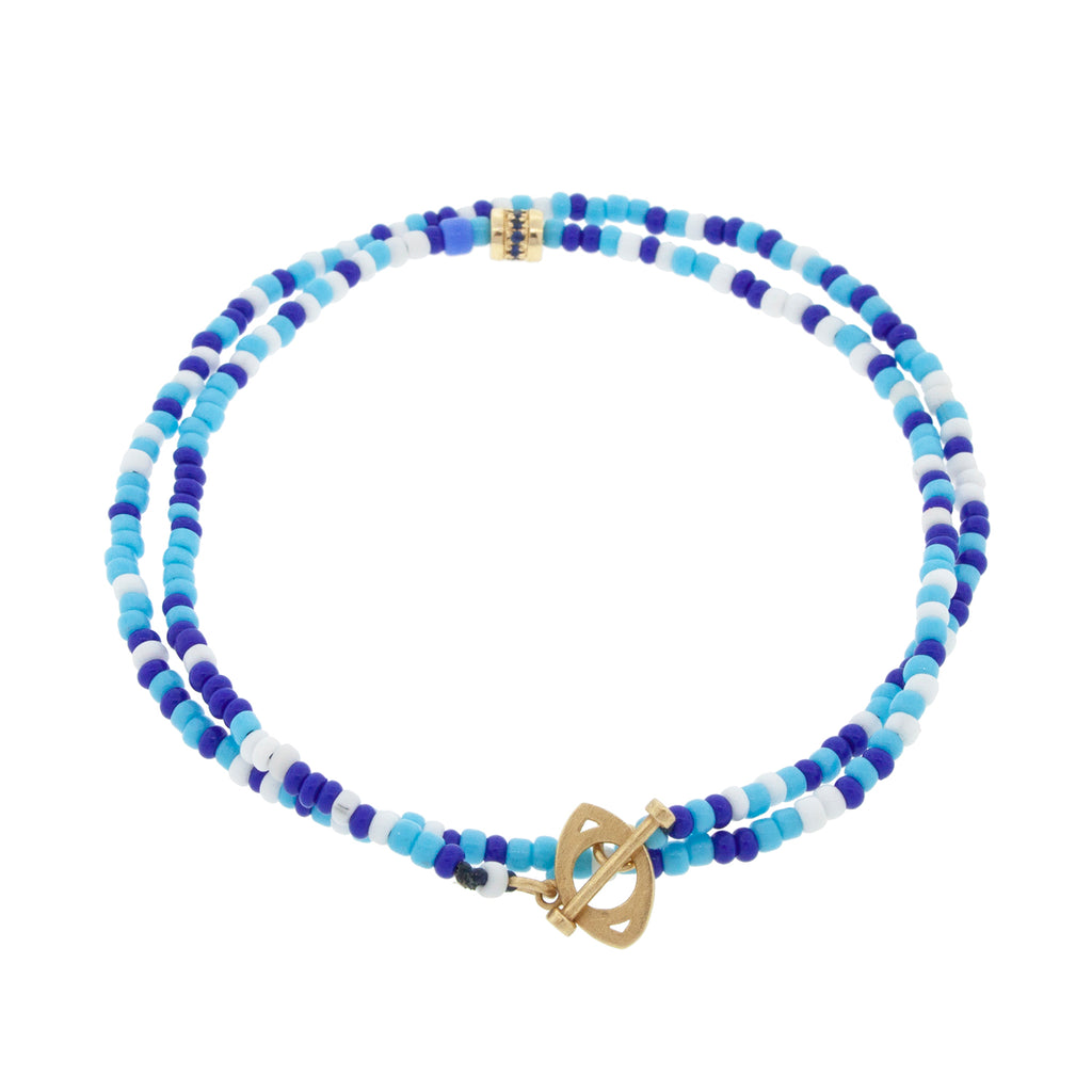 LUIS MORAIS 14K yellow gold evil eye toggle clasp with a short roll bead with blue sapphires on a double wrap beaded bracelet